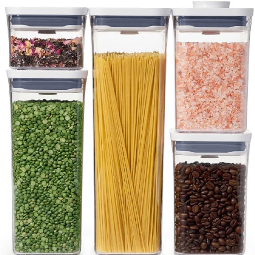 Four airtight glass containers filled with different types of dry grains and legumes.