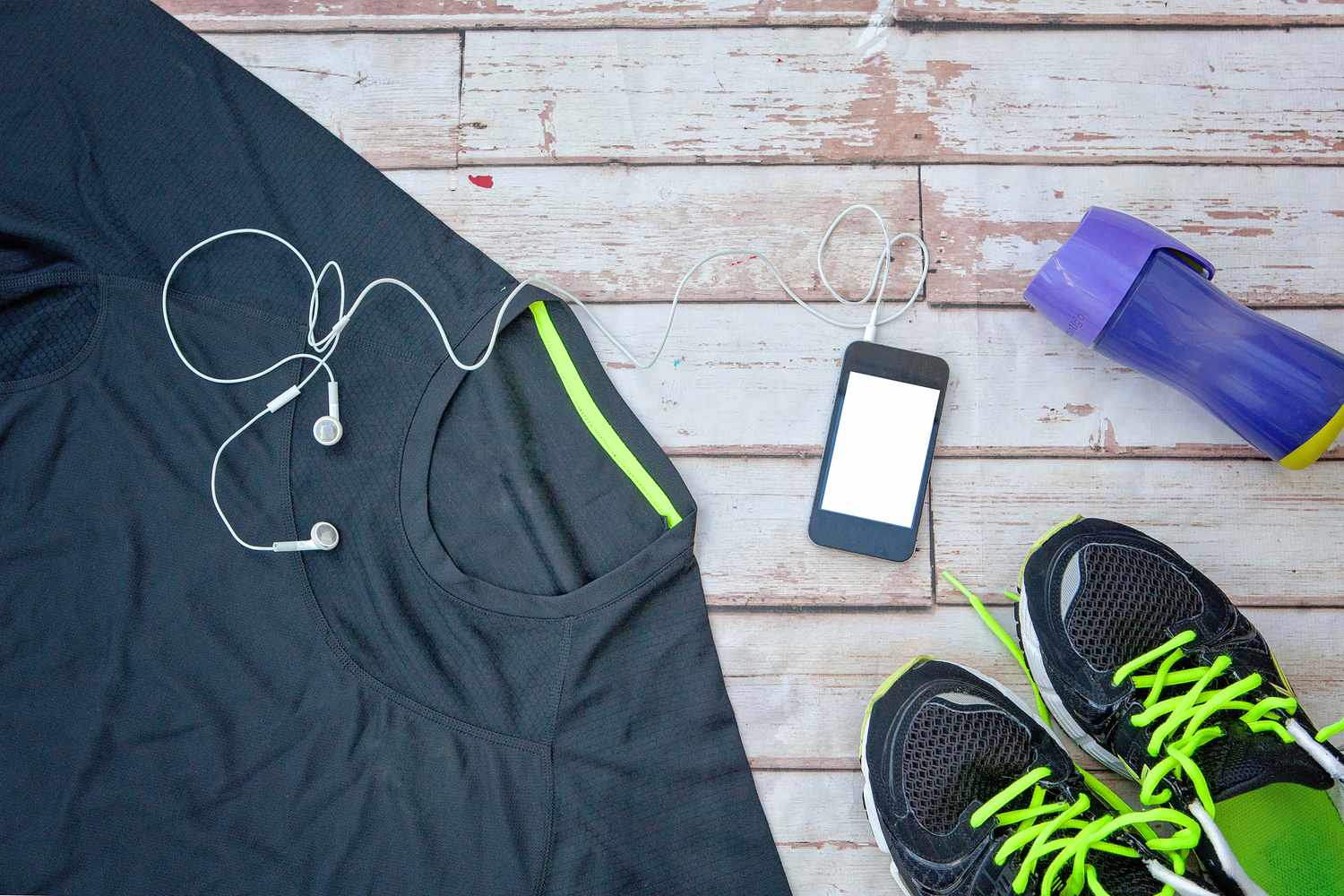 A professional flat-lay of running gear featuring high-performance shoes, a moisture-wicking shirt, and hydration accessories on a wooden background.