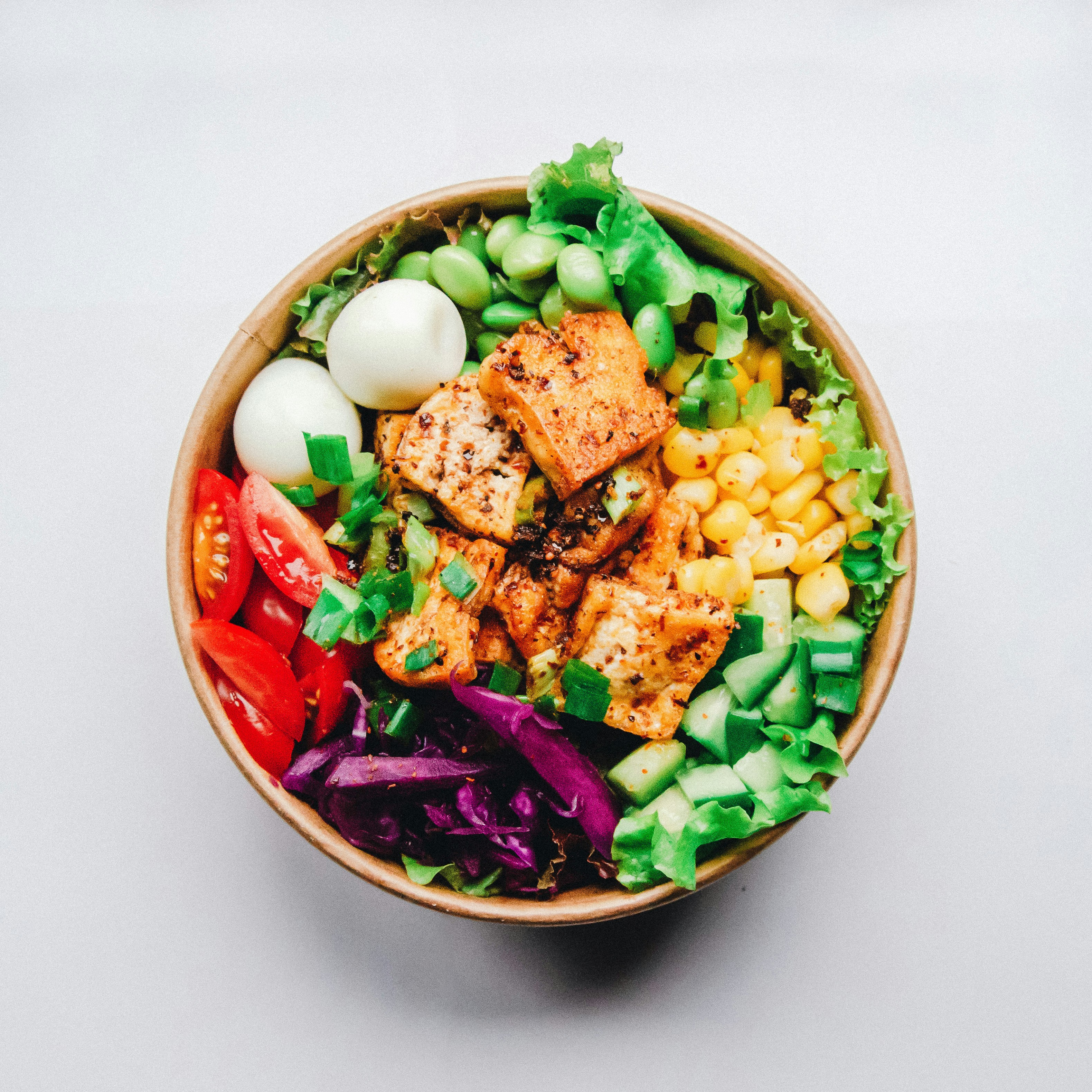 A colorful salad bowl with mixed greens, vegetables, and plant-based protein sources.