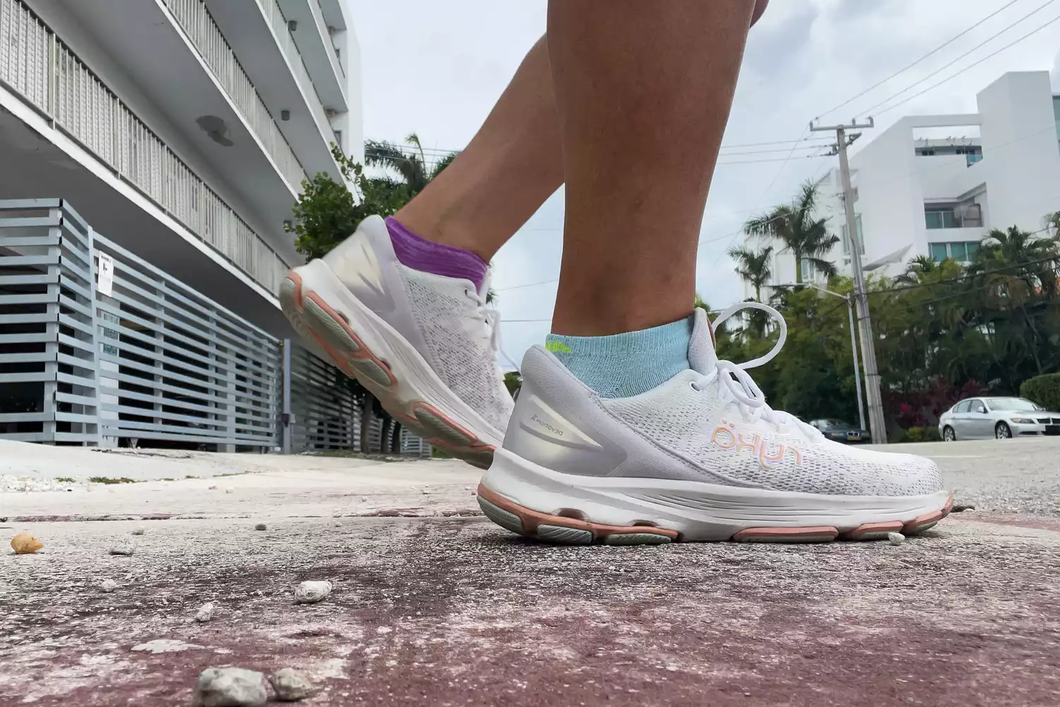A person walking on a city sidewalk wearing white Ryka Devotion X sneakers.