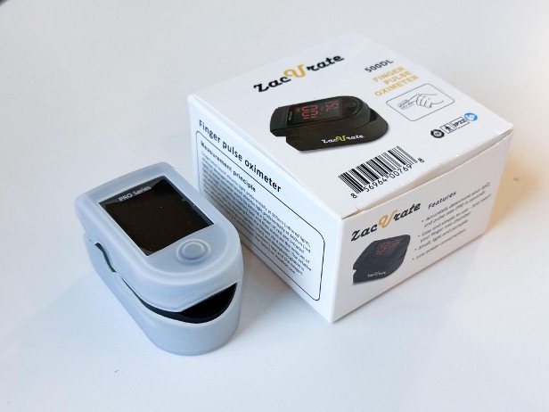 A person inserting their finger into the soft silicone chamber of a pulse oximeter.