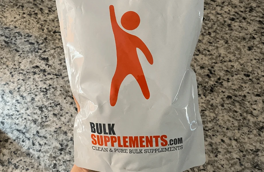 A person holding a large white bag of organic beetroot powder supplement.