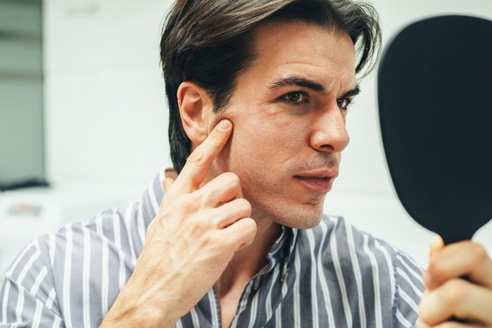 A man checking his skin condition in a mirror.