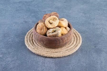 A close-up of a bowl filled with orange dried apricots.