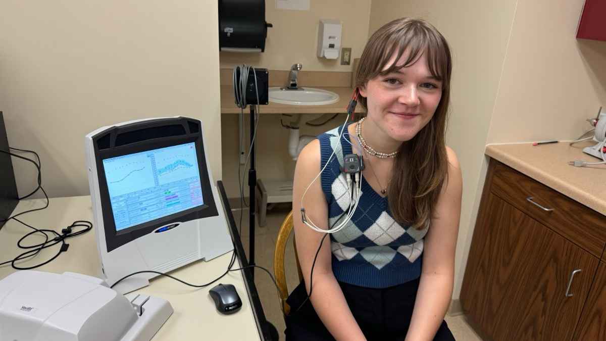 A professional clinician performing a real-ear measurement fitting on a patient.