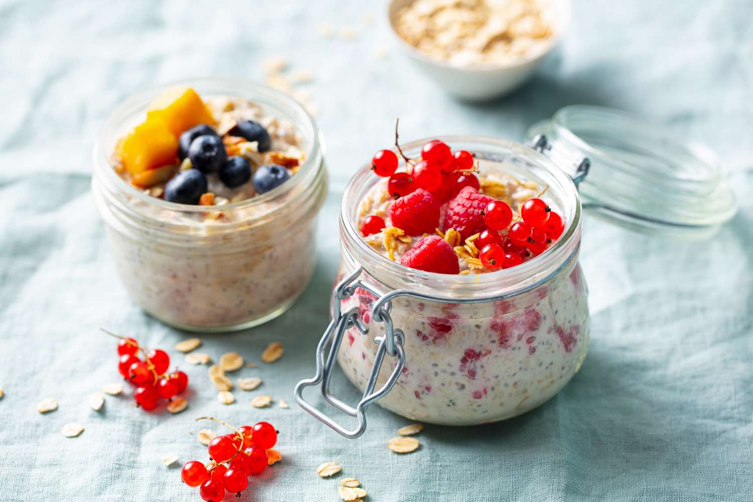 Two jars of fruit-topped oatmeal on a rustic fabric background.