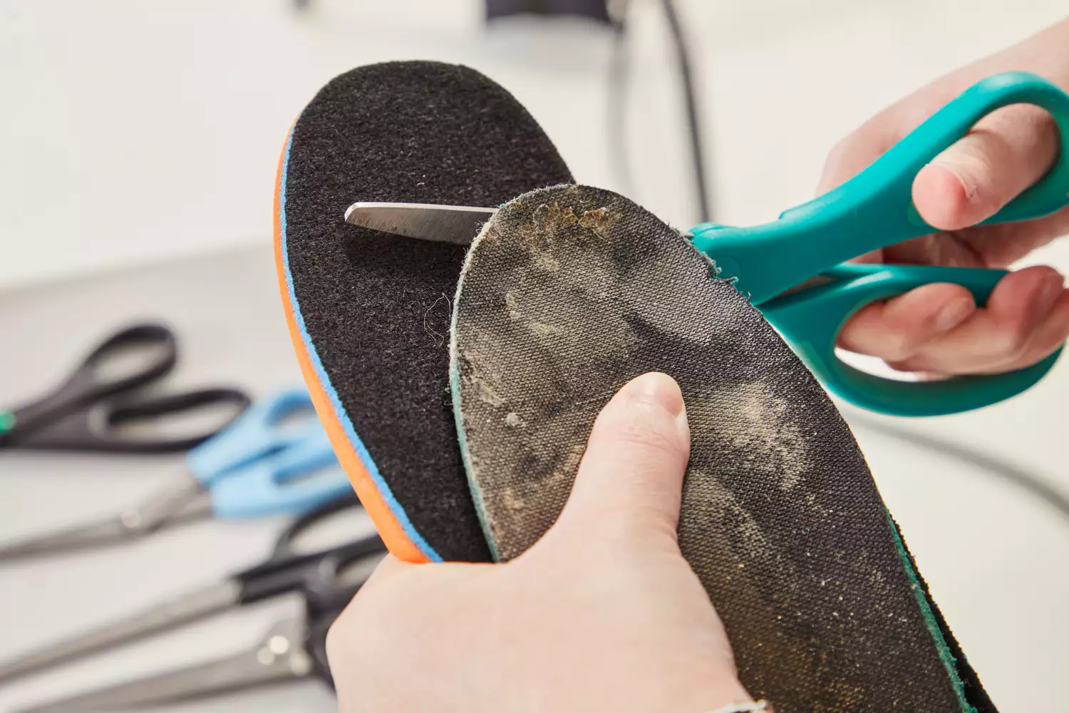 A person using scissors to carefully trim a shoe insole for a better fit.