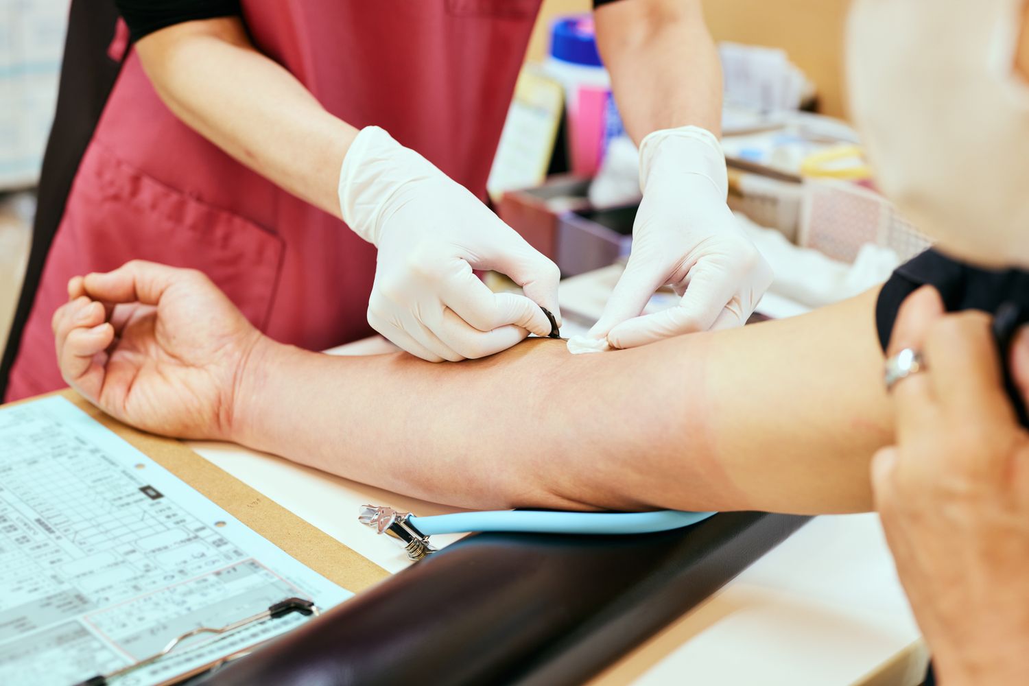 A close-up view of a medical professional collecting a blood sample from a patient's arm.