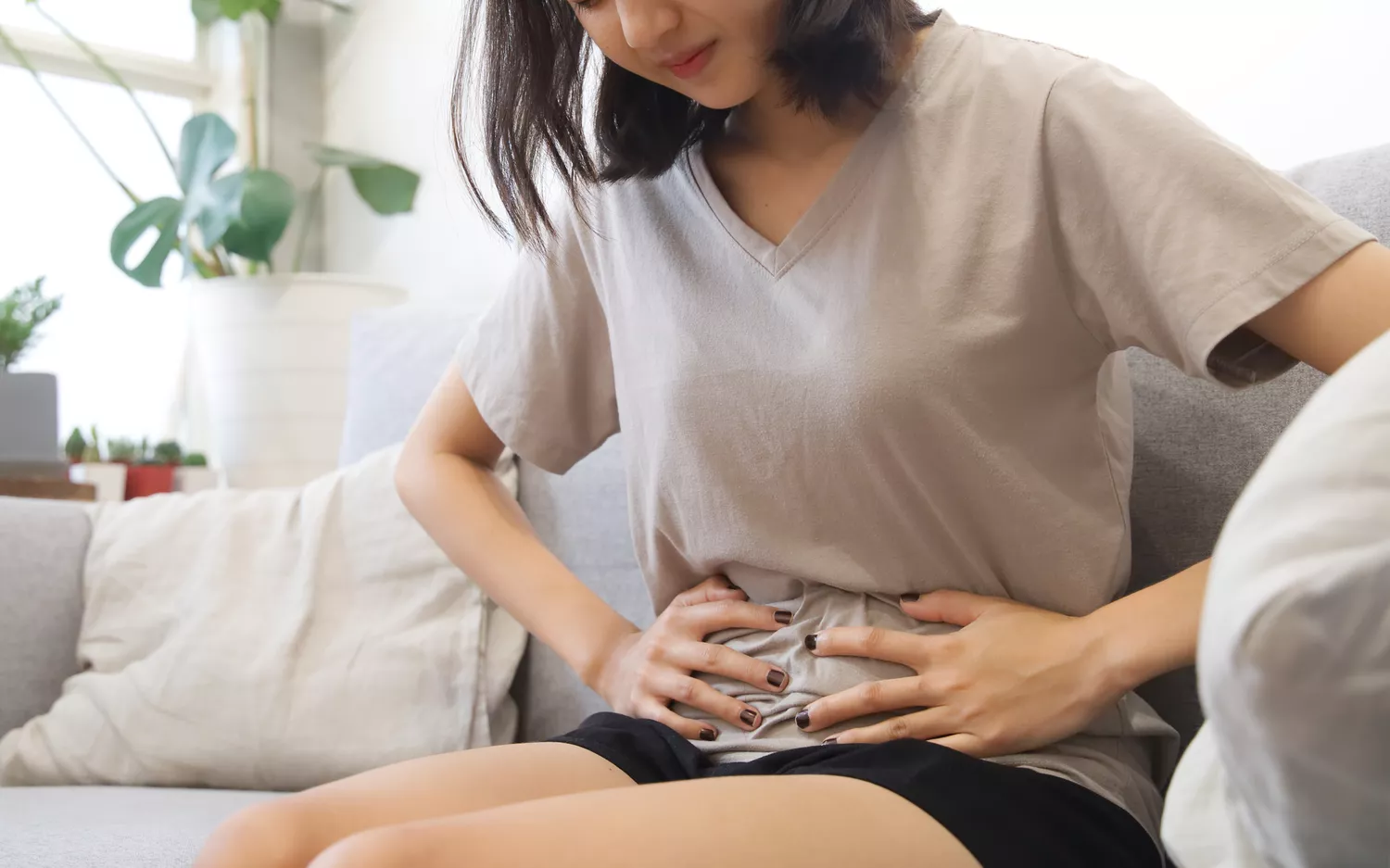 A woman holding her stomach in discomfort, symbolizing the physical impact of metabolic syndrome.