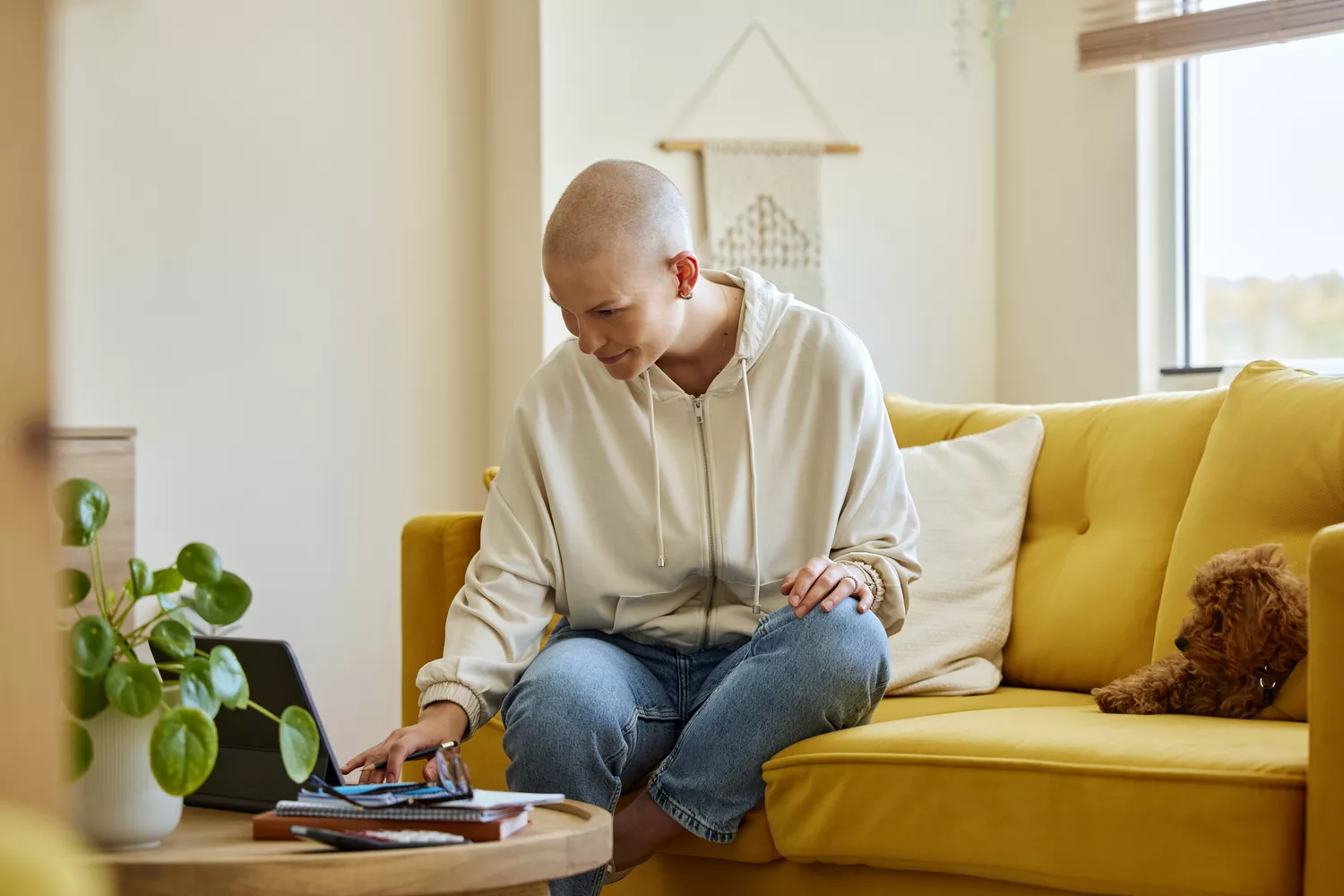 A woman at home thoughtfully researching medical and financial resources on her laptop.