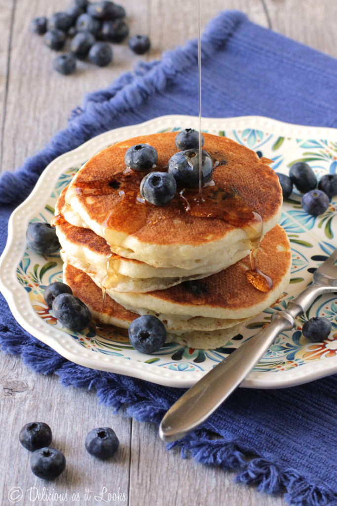 A stack of fluffy blueberry pancakes topped with fresh fruit.