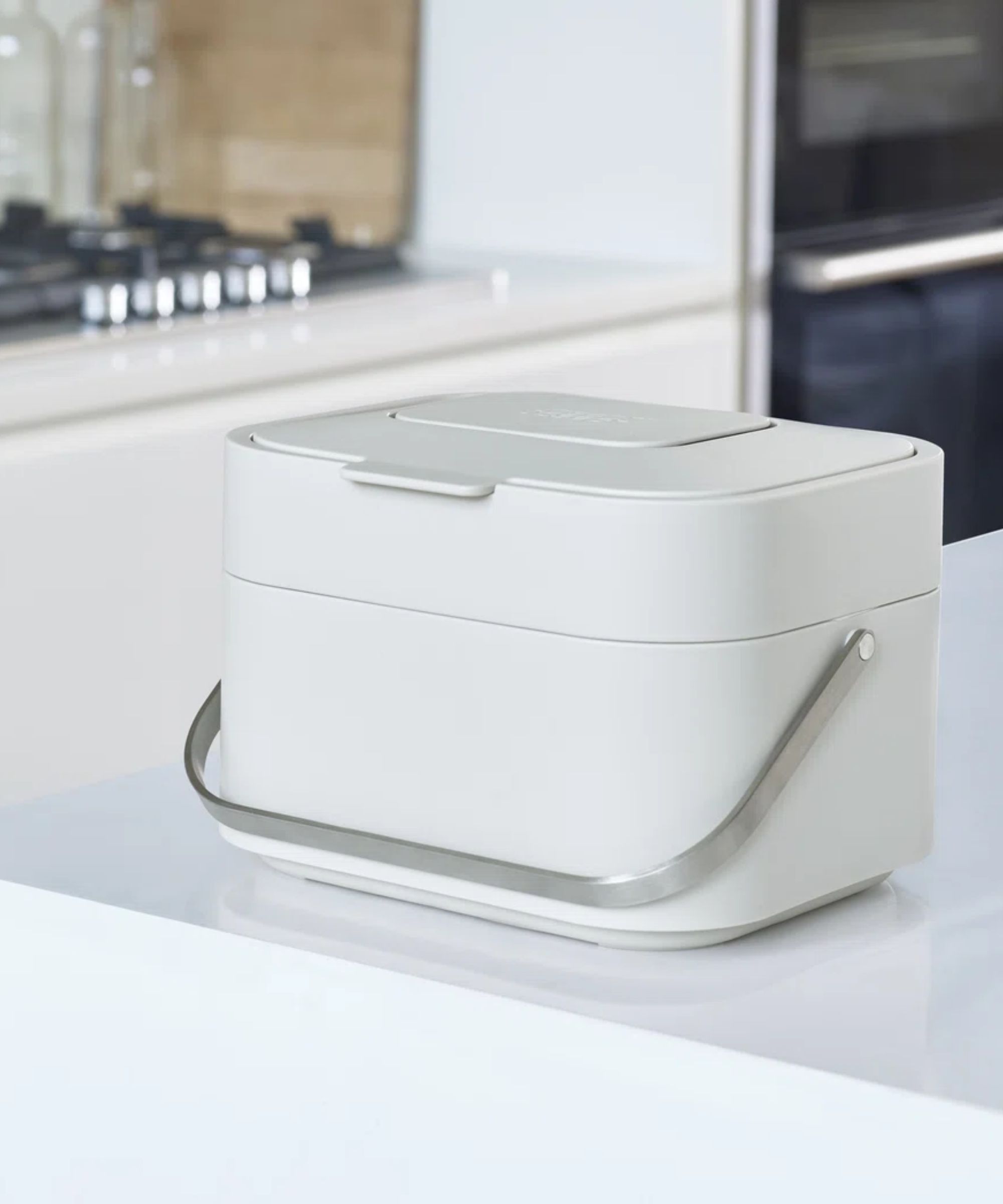 A modern white countertop compost bin with a wooden lid.