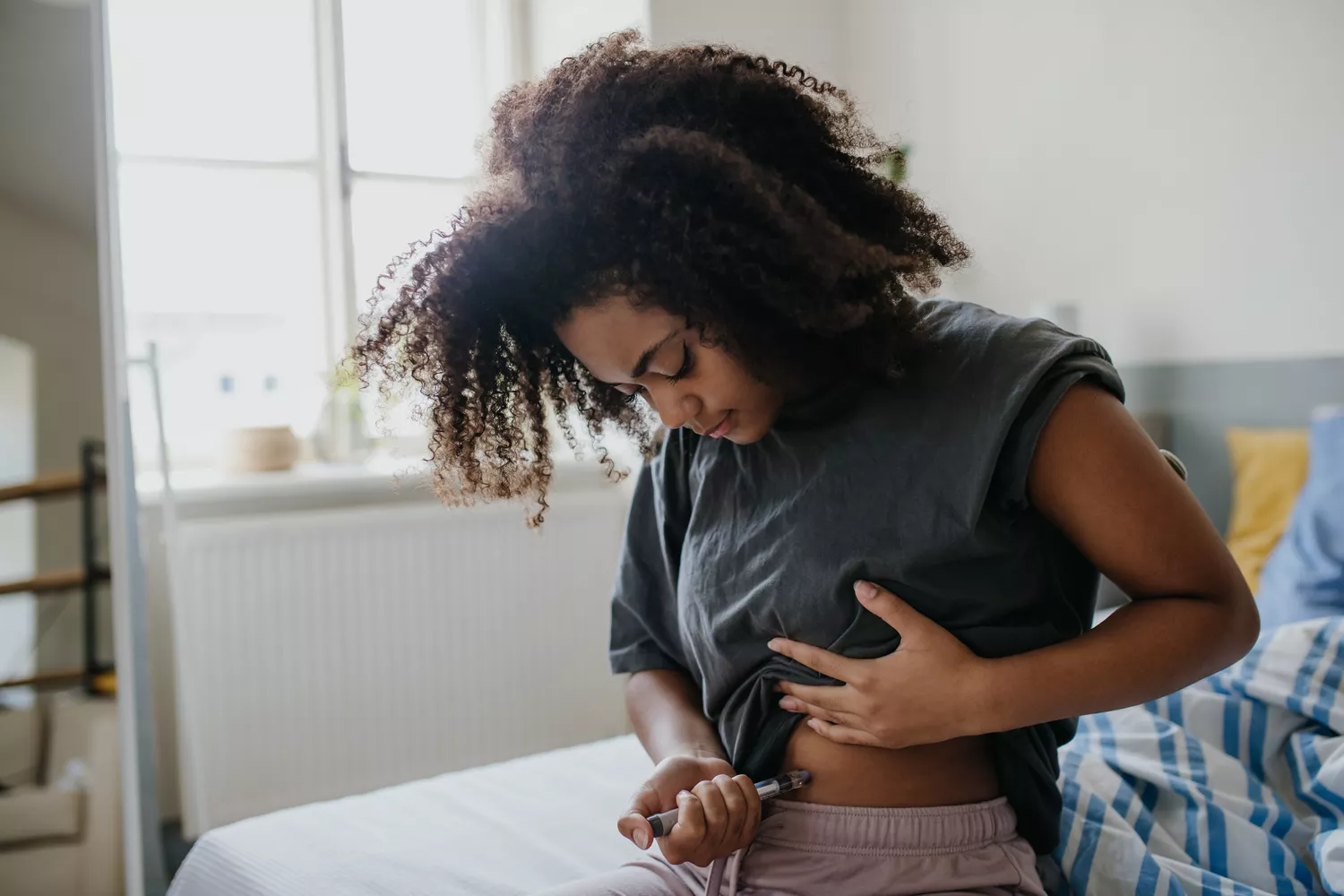 A person using a medication pen to perform a subcutaneous injection in the abdomen.