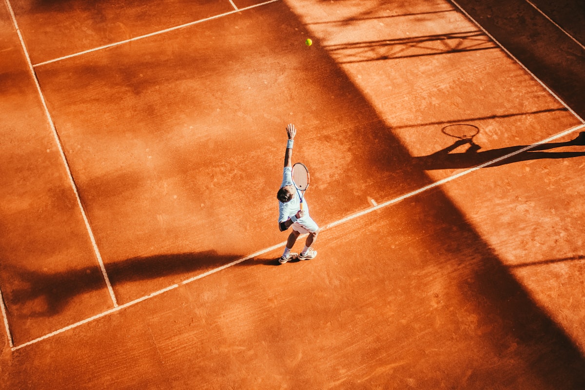 Athlete performing explosive lateral shuffle drills using orange cones on a tennis court.