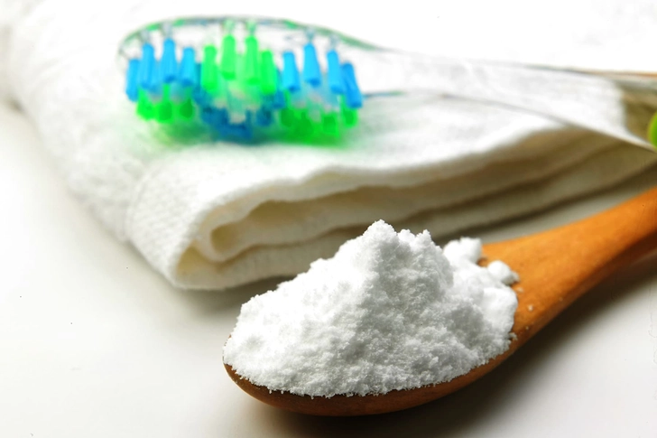 White baking soda powder applied to the bristles of a manual toothbrush.