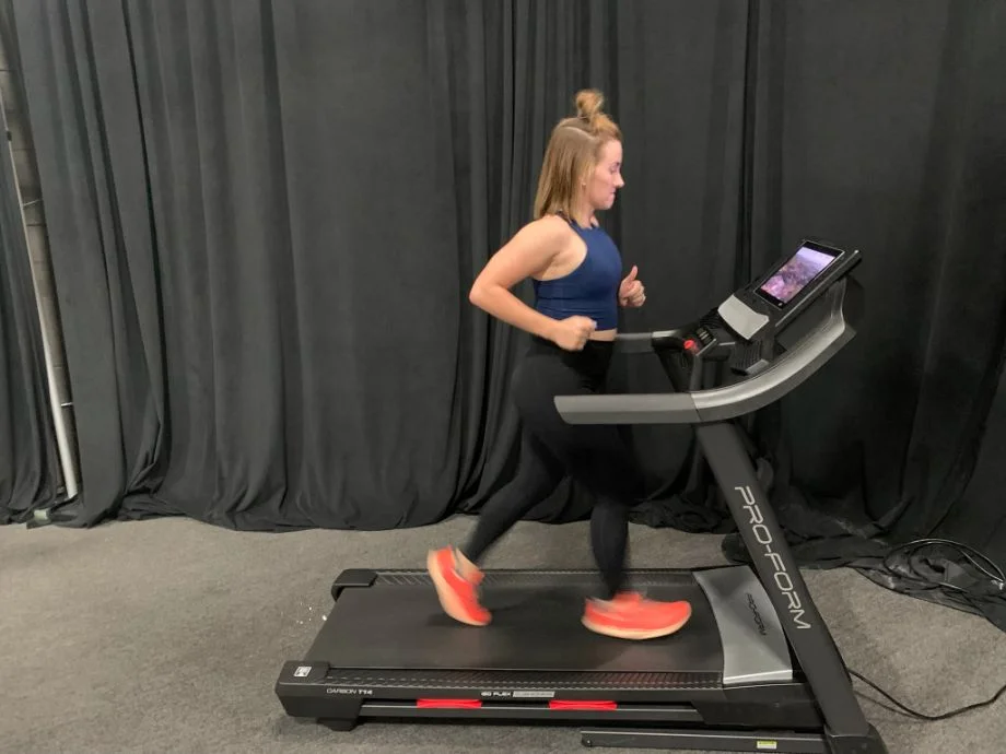 A woman running on a treadmill wearing high-waisted Fabletics leggings.