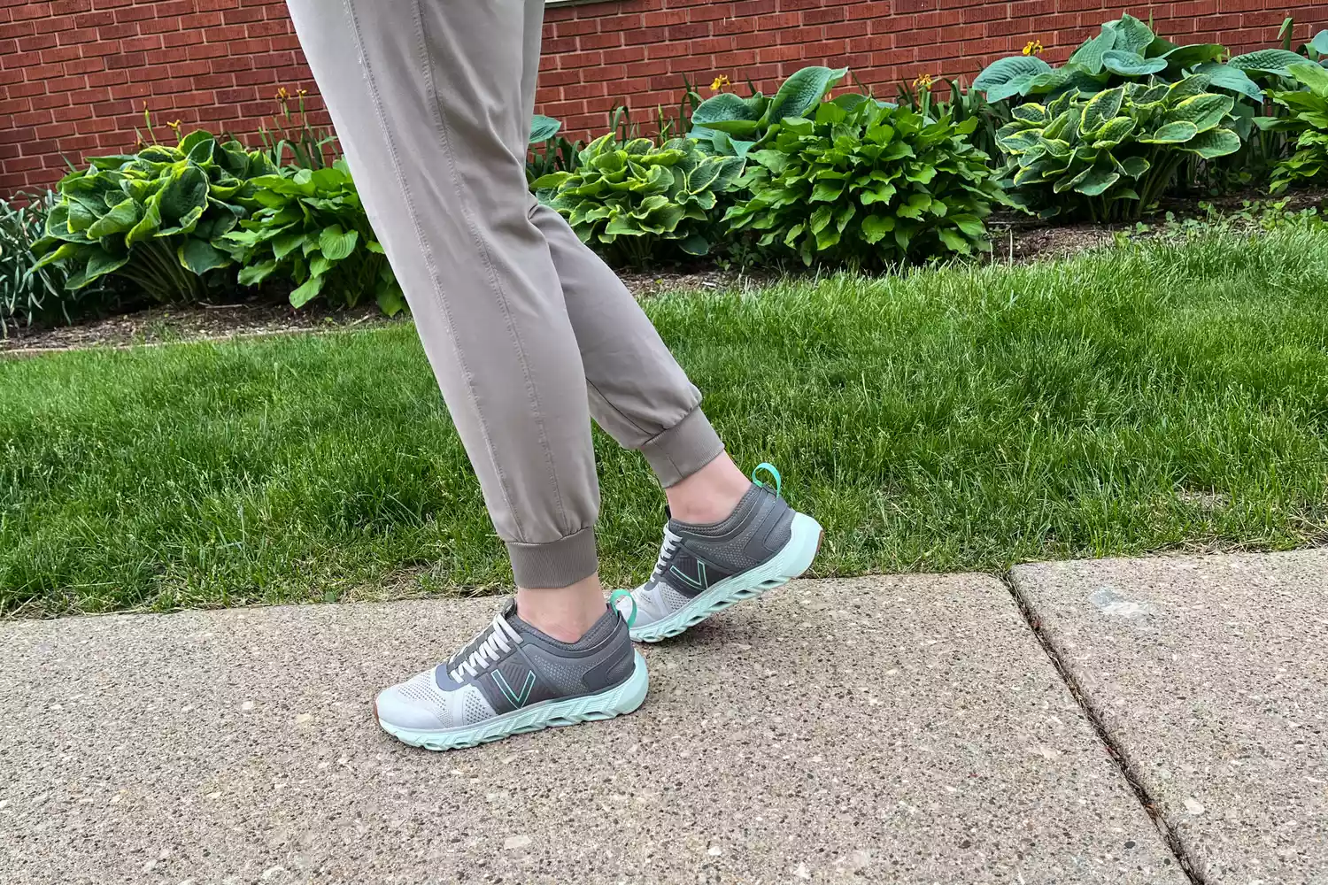 A person walking near a garden wearing Vionic walking sneakers.