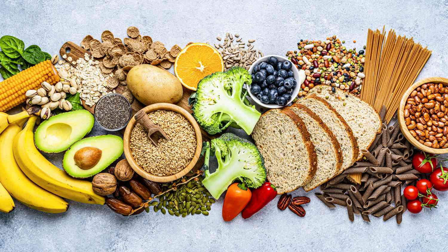 Top-down view of a colorful variety of fruits, vegetables, grains, and legumes arranged on a table.