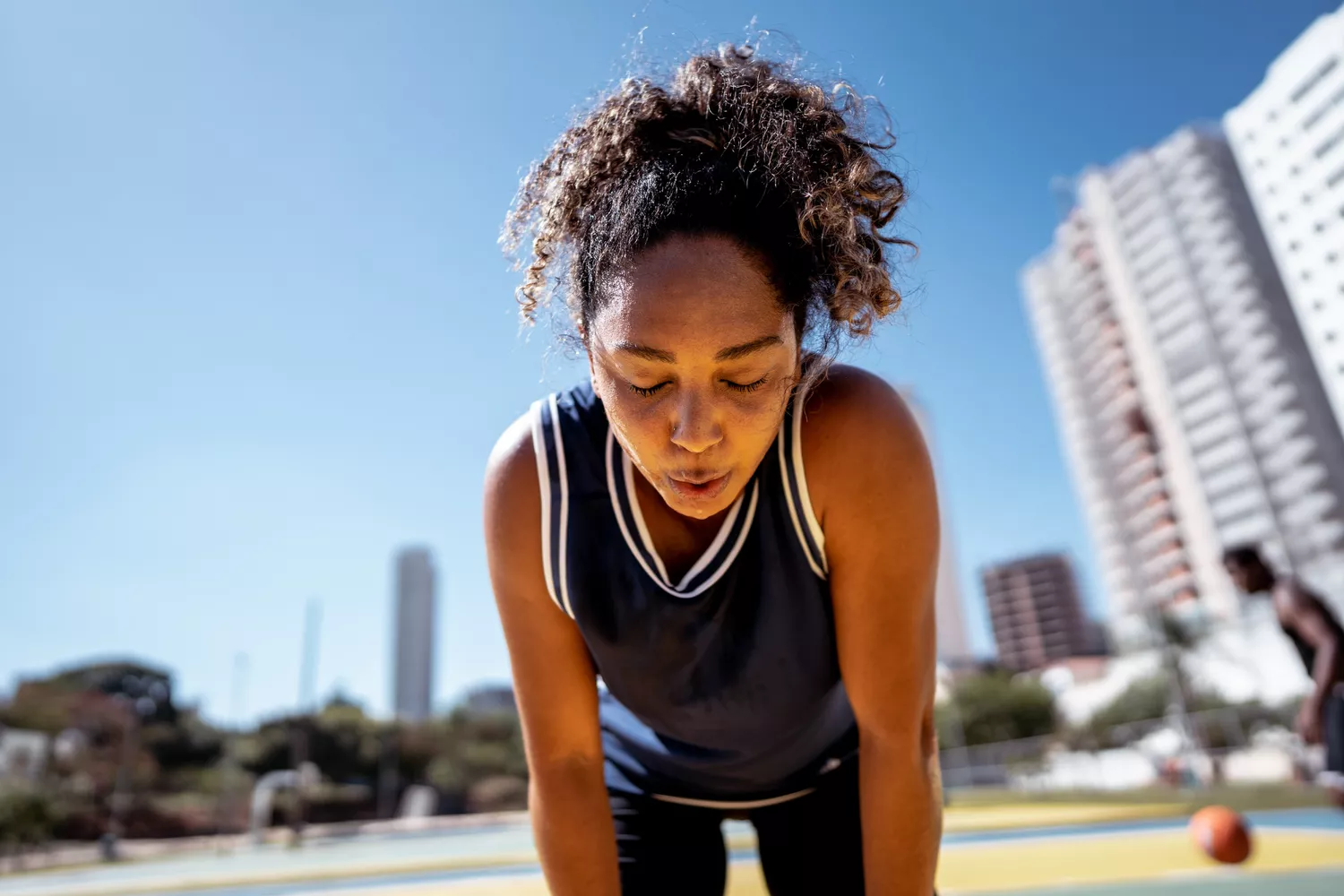 A woman taking a break during a basketball game, representing physical activity.